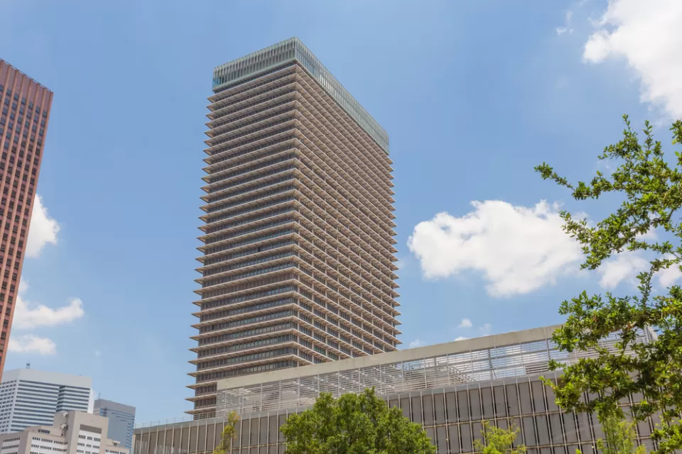 A high-rise building is seen fromt he ground, framed by an assortment of tall and shorter buildings.